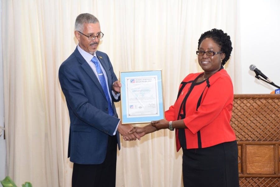 Minister of Business Dominic Gaskin hands the ISO 9001:2015 certificate to Candelle Bostwick, Director of the Guyana National Bureau of Standards, April 2018