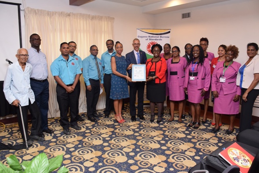 Candelle Bostwick with the staff of the Guyana National Bureau of Standards receiving the ISO 9001:2015 certificate